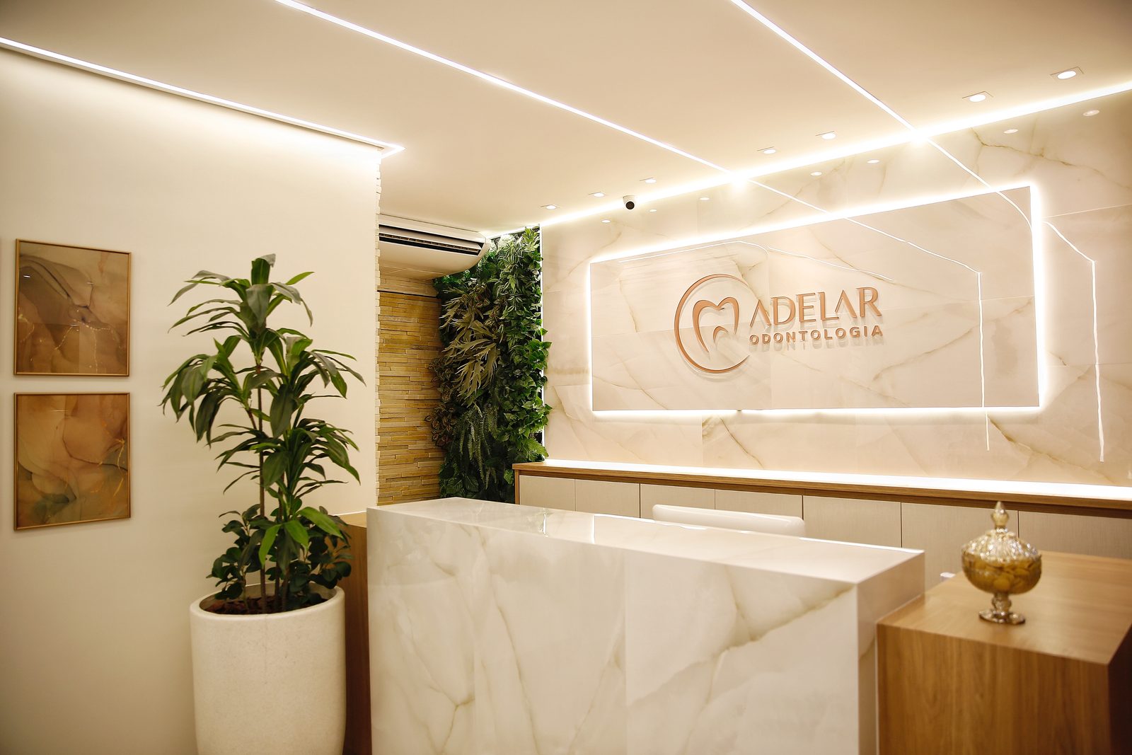 Recepção da Adelar Odontologia com o logo retroiluminado e mármore